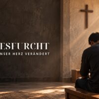 Gottesfurcht: Ein Mann sitzt mit gesenktem Kopf im Gebet vor einem schlichten Kreuz im warmen Tageslicht.